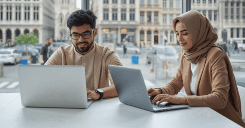 شاب وفتاة من جنسيات مختلفة يجلسان في مساحة عمل حديثة في بروكسل، يعملان على حواسيب محمولة ويبحثان عن وظائف عبر الإنترنت، تظهر في الخلفية معالم بلجيكية مميزة مثل ساحة غراند بلاس ومباني الاتحاد الأوروبي، أجواء مهنية عصرية، إضاءة طبيعية، أسلوب واقعي عالي الجودة، يعكس التنوع الثقافي وفرص العمل في بلجيكا، تصميم نظيف مناسب لمقال مهني وسوق العمل.