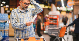 رجل يتسوق في سوبر ماركت بلجيكي ويشاهد فاتورة الاسعار بشكل مصدور بجانب المحاسب