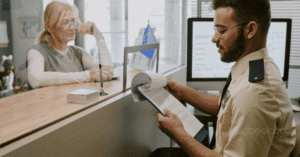 صورة واقعية لمكتب هجرة أو إدارة حكومية في بلجيكا، يظهر فيها موظف يستقبل متقدّم للحصول على تصريح عمل،