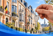 يد تحمل مفتاح منزل أمام مبانٍ سكنية في مشهد مستوحى من بروكسل مع العلم البلجيكي