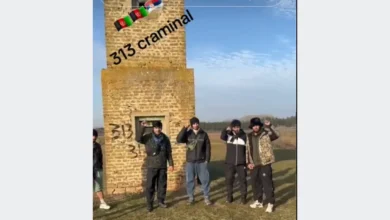 مجموعة أشخاص يقفون أمام مبنى حجري وتظهر على الصورة عبارة 313 criminal وأعلام أفغانستان