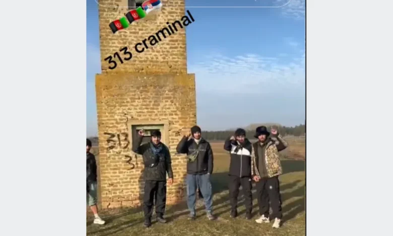 مجموعة أشخاص يقفون أمام مبنى حجري وتظهر على الصورة عبارة 313 criminal وأعلام أفغانستان