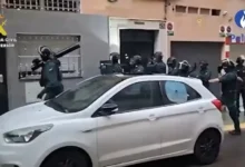 عناصر مسلحة من الحرس المدني الإسباني أمام مبنى خلال عملية أمنية مع سيارة بيضاء في المقدمة