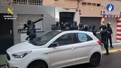 عناصر مسلحة من الحرس المدني الإسباني أمام مبنى خلال عملية أمنية مع سيارة بيضاء في المقدمة